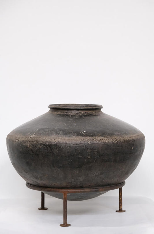 Gammel smuk lerkrukke på jernstativ